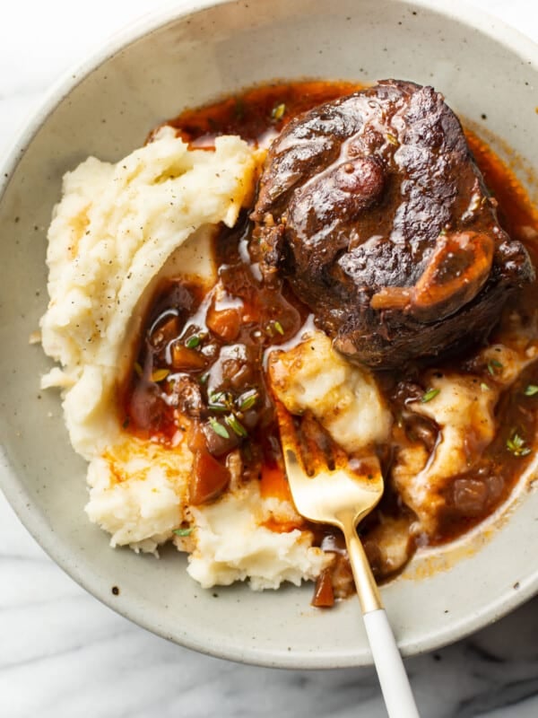 a bowl with crockpot red wine braised short ribs over mashed potatoes with a fork