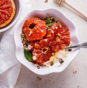 bowl of grapefruit brulee breakfast bowl with a spoon beside a honey dipper