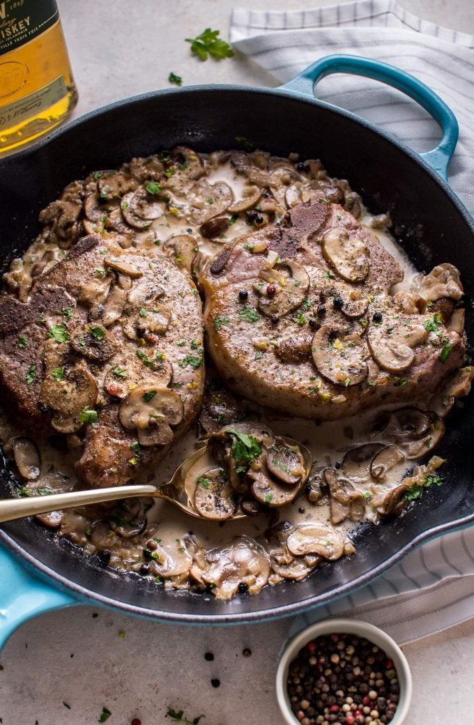 creamy Irish whiskey pork chops with a serving spoon in a skillet