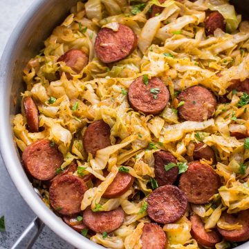 a metal skillet with sauteed sausage and cabbage