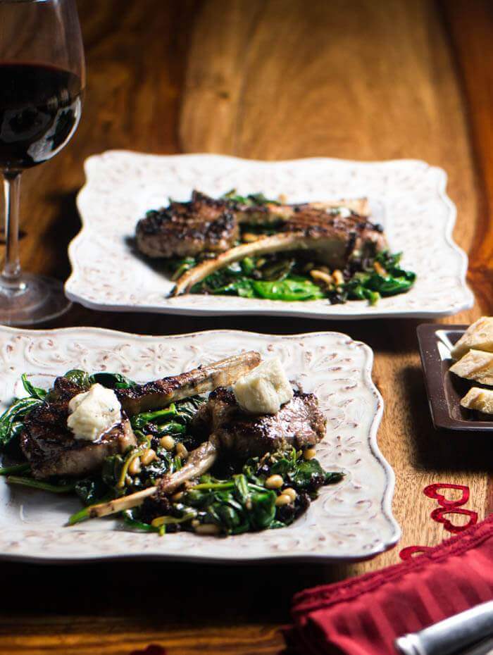 two plates with grilled lamb and a glass of red wine