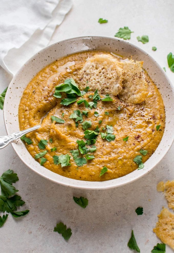 bowl of cauliflower and butternut squash soup with parsley garnish