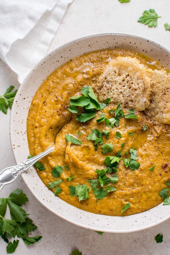 close-up of roasted butternut squash and cauliflower soup with a spoon and garnished with parsley