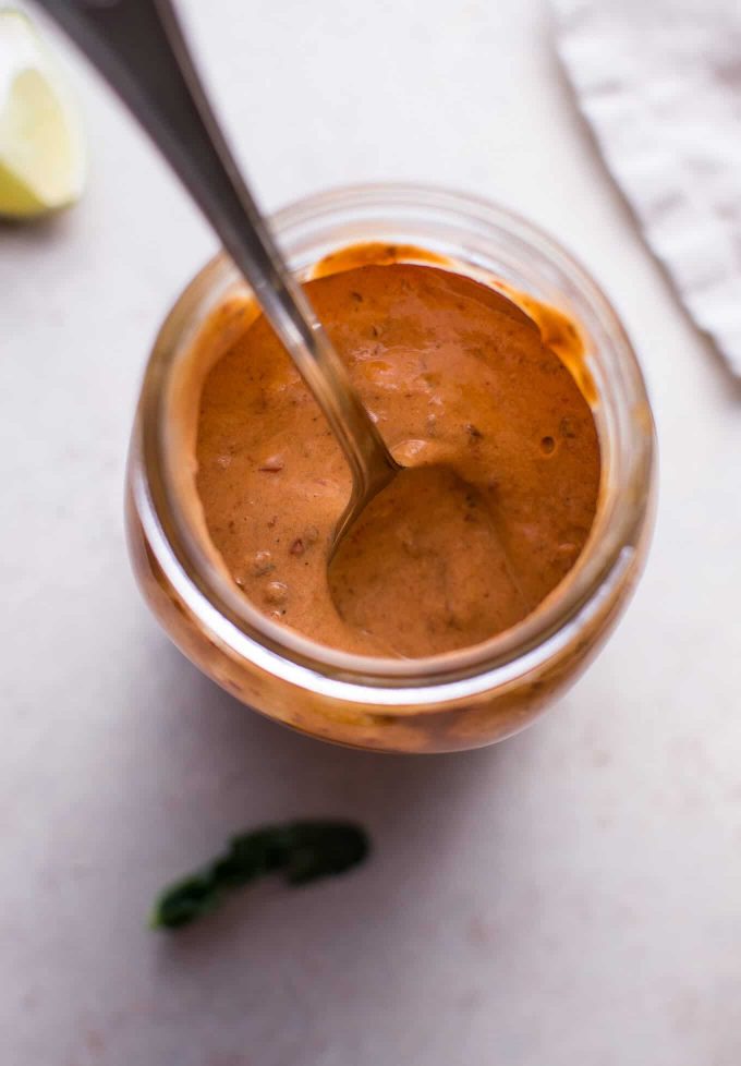 glass jar with homemade spicy chipotle dressing and a spoon