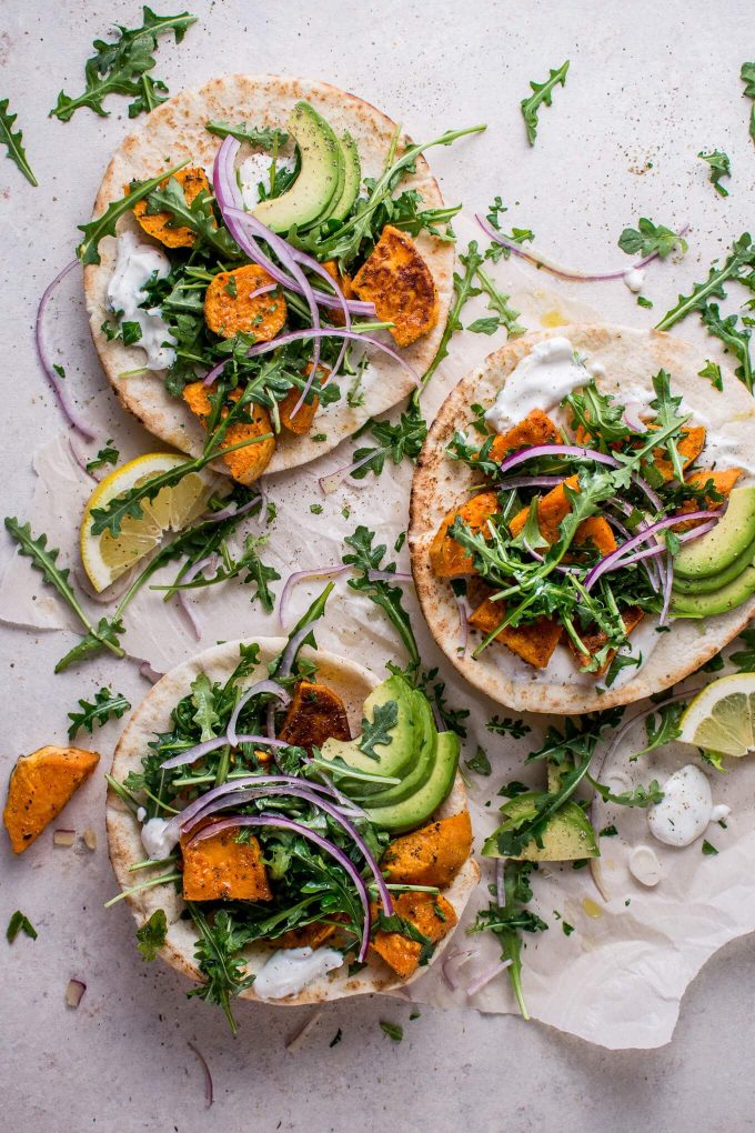 roasted sweet potato pitas with arugula and garlic dressing on a counter