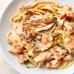 close-up of white bowl with creamy lemon and fresh tomato salmon pasta