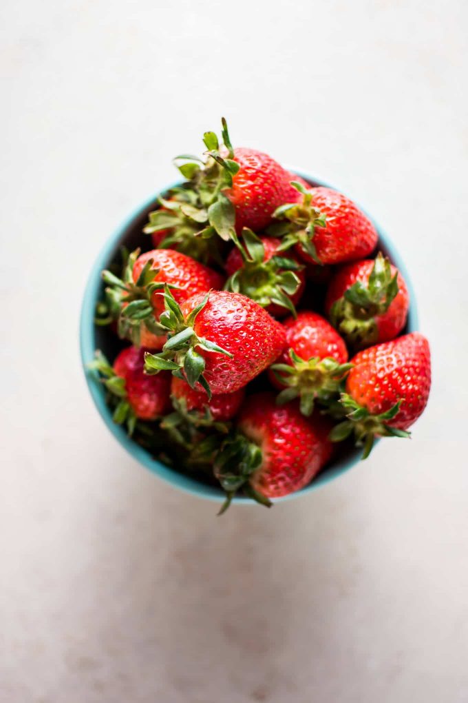 a small teal bowl of strawberries