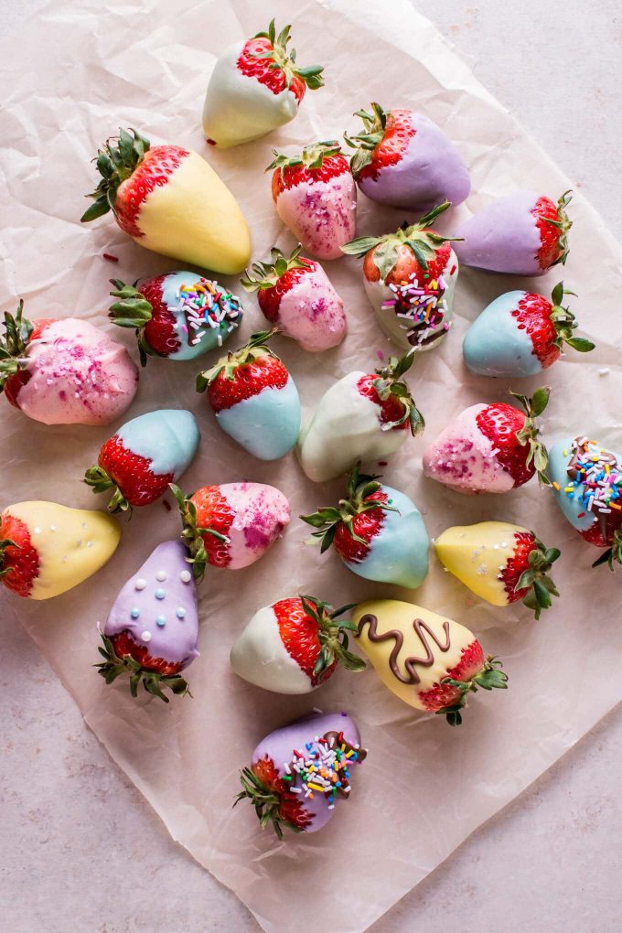several Easter pastel-colored chocolate covered strawberries on parchment paper