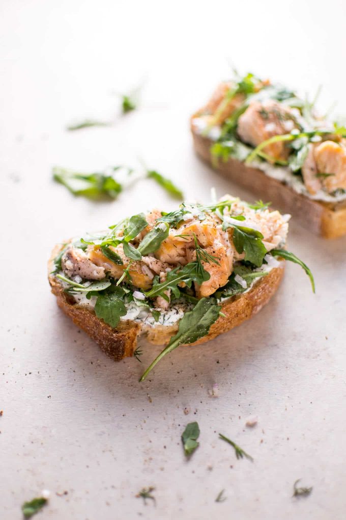 open-faced sandwich on a counter with lemon, dill, shallots, and arugula