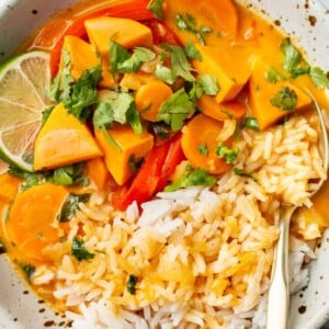 a bowl of thai sweet potato curry over rice in a bowl with a fork