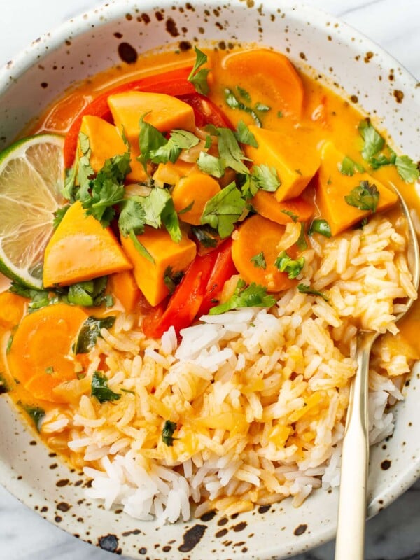 a bowl of thai sweet potato curry over rice in a bowl with a fork