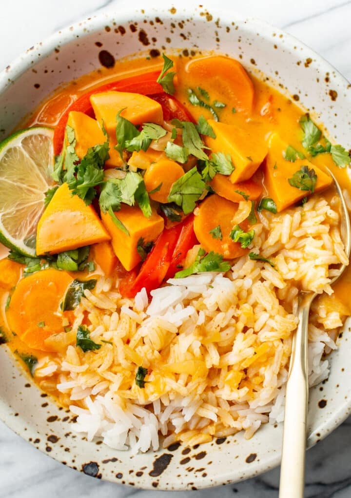 a bowl of thai sweet potato curry over rice in a bowl with a fork