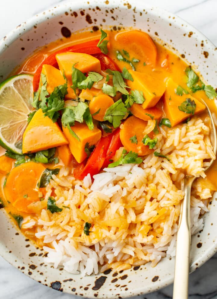 a bowl of thai sweet potato curry over rice in a bowl with a fork