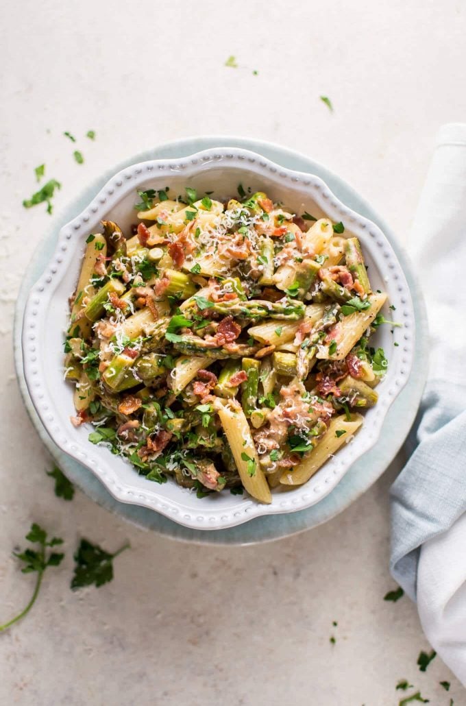 bowl of spring asparagus bacon pasta beside cloth napkin