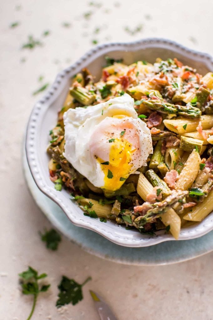 bowl with asparagus and bacon pasta topped with a poached egg