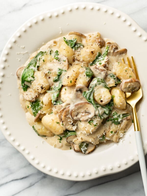 a bowl of creamy mushroom spinach gnocchi with a fork