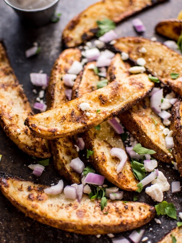 These Greek loaded baked potato wedges make a tasty appetizer or side dish. Served with tzatziki for dipping!