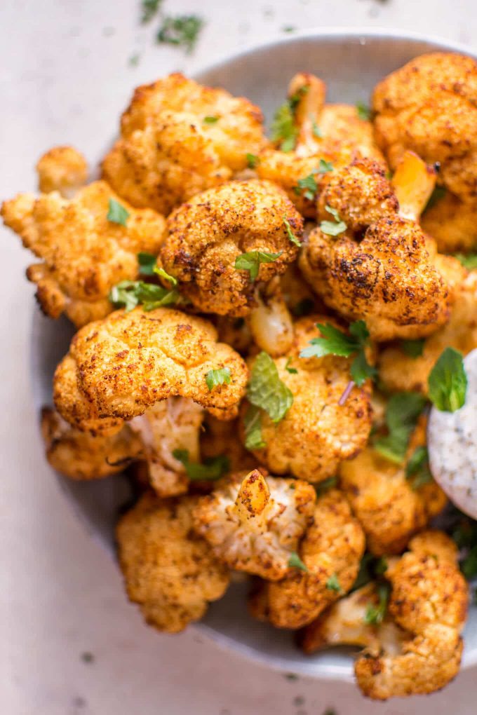 close-up of roasted cauliflower bites in a bowl garnished with mint