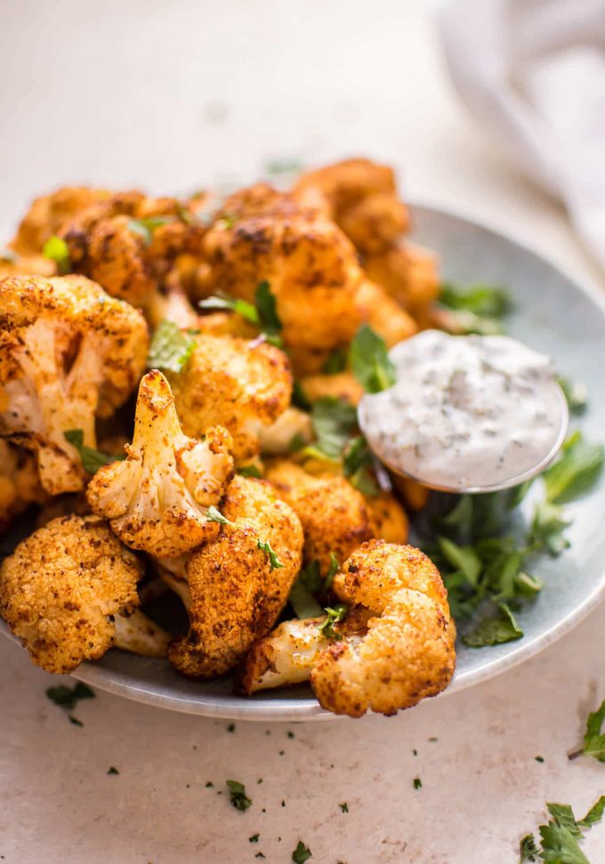 close-up of roasted cauliflower bites beside container of mint dip