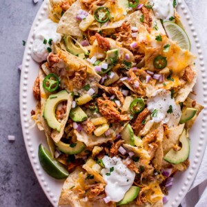 These tropical chicken nachos are a fun and tasty appetizer! Sweet and spicy chicken, pineapple, lime, avocado, sour cream, jalapenos, and lots of gooey cheese are a great combination of freshness and comfort.