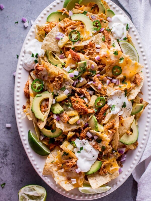 These tropical chicken nachos are a fun and tasty appetizer! Sweet and spicy chicken, pineapple, lime, avocado, sour cream, jalapenos, and lots of gooey cheese are a great combination of freshness and comfort.