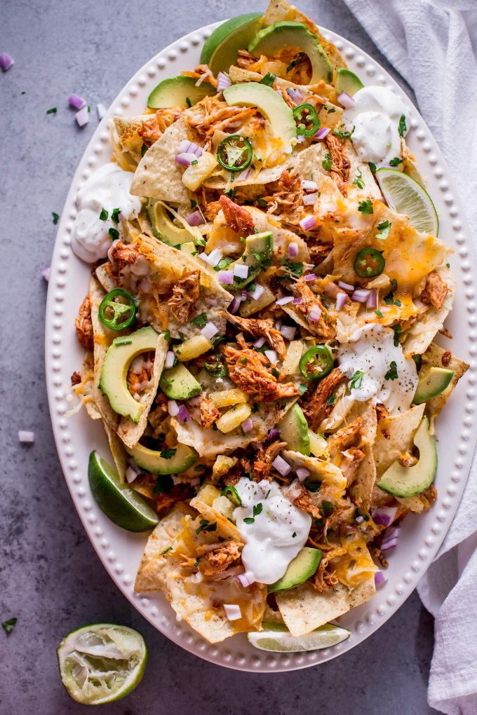 oval serving platter with tropical chicken nachos topped with pineapple, avocado, sour cream, and jalapenos