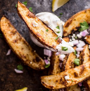 These Greek loaded baked potato wedges make a tasty appetizer or side dish. Served with tzatziki for dipping!