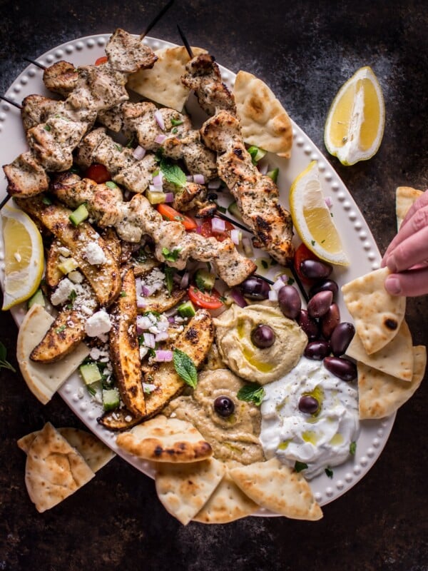 The Ultimate Greek Chicken Souvlaki Platter is loaded with tender grilled chicken skewers, pita bread, Greek potato wedges, hummus, tzatziki, melitzanosalata, kalamata olives, feta, and other goodies. The perfect meze assortment for any feast or party!