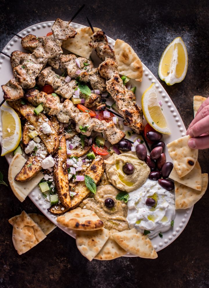 The Ultimate Greek Chicken Souvlaki Platter is loaded with tender grilled chicken skewers, pita bread, Greek potato wedges, hummus, tzatziki, melitzanosalata, kalamata olives, feta, and other goodies. The perfect meze assortment for any feast or party!