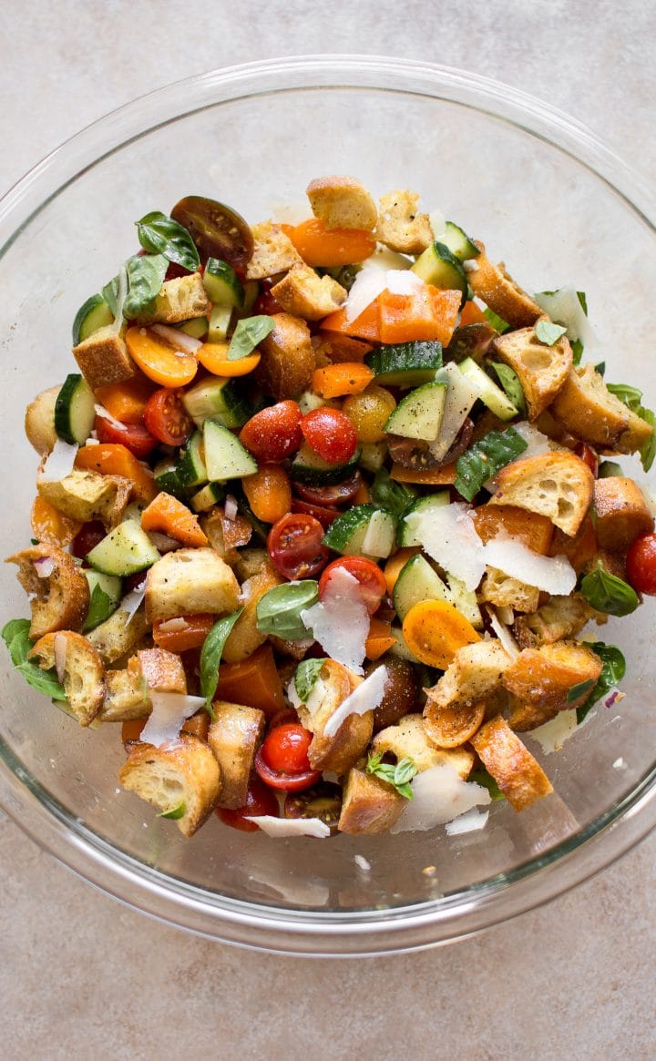 panzanella salad ingredients in a clear glass mixing bowl