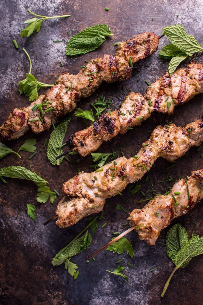 four grilled Vietnamese lemongrass pork tenderloin skewers with mint garnish