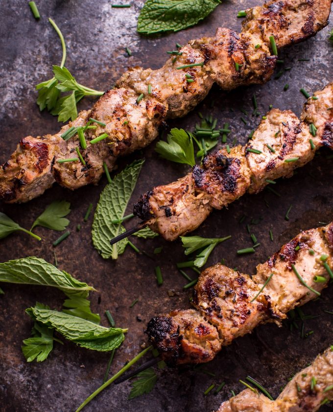 close-up of three grilled Vietnamese lemongrass pork tenderloin skewers with mint leaves