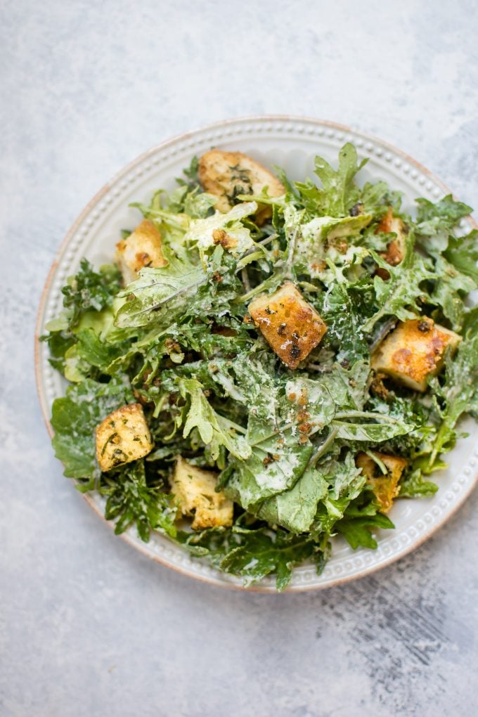 close-up of baby kale salad with lemon tahini dressing and homemade garlic parmesan croutons