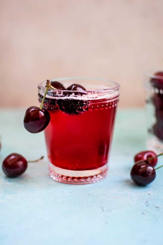 glass with homemade cherry vanilla soda and several cherries