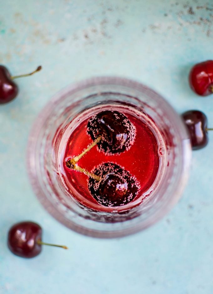 close-up of homemade cherry vanilla soda in a glass with a pair of cherries