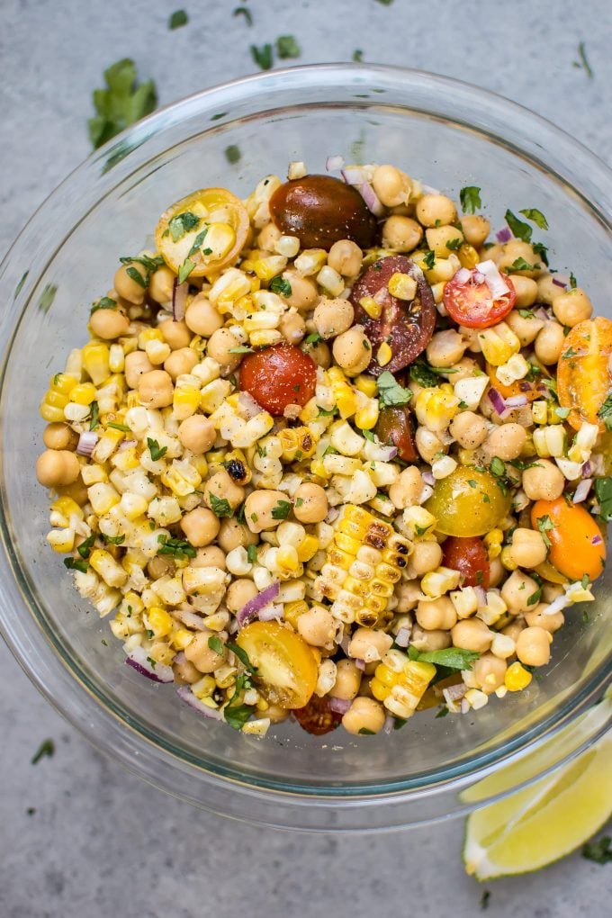 close-up of grilled corn, chickpea, and tomato salad in a glass bowl