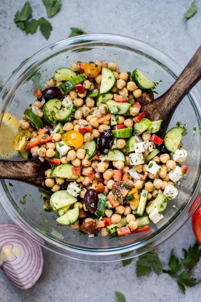 close-up of bowl of Mediterranean chickpea salad with wooden salad utensils