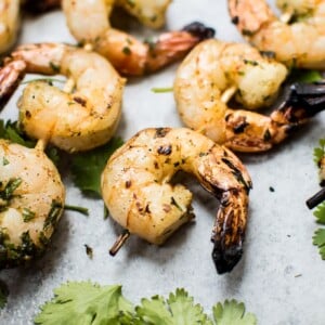 grilled tequila lime shrimp skewers next to cilantro leaves