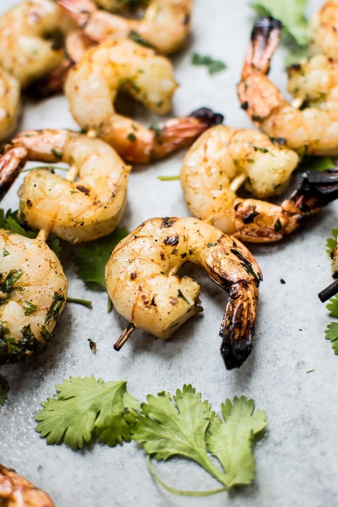 grilled tequila lime shrimp skewers next to cilantro leaves