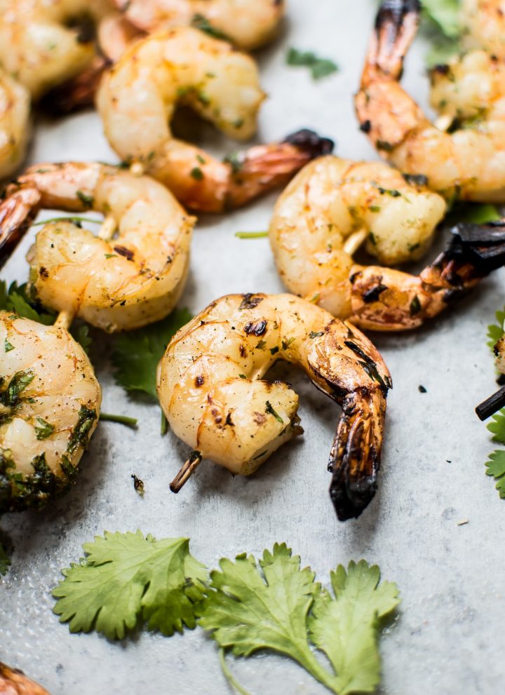 grilled tequila lime shrimp skewers next to cilantro leaves