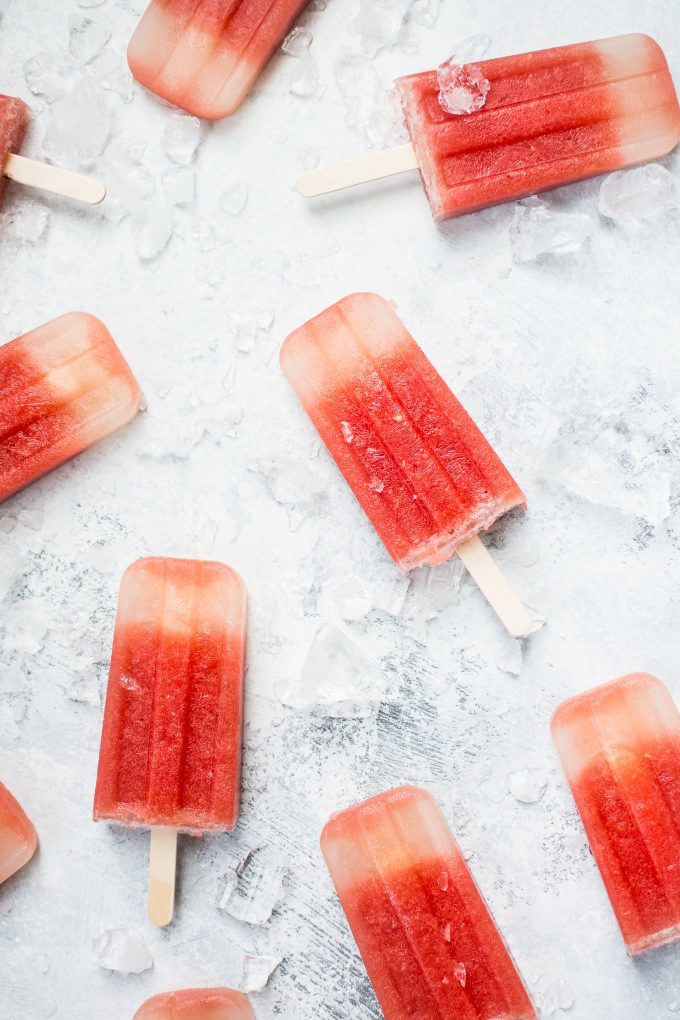 watermelon margarita popsicles on a counter with ice cubes