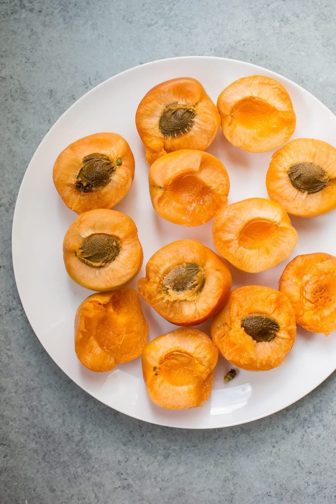 several apricots cut in half on a white plate