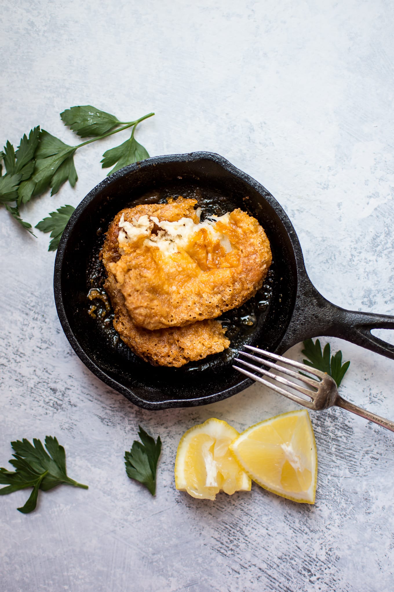 tiny frying pan with saganaki Greek fried cheese, a fork, and lemon wedges