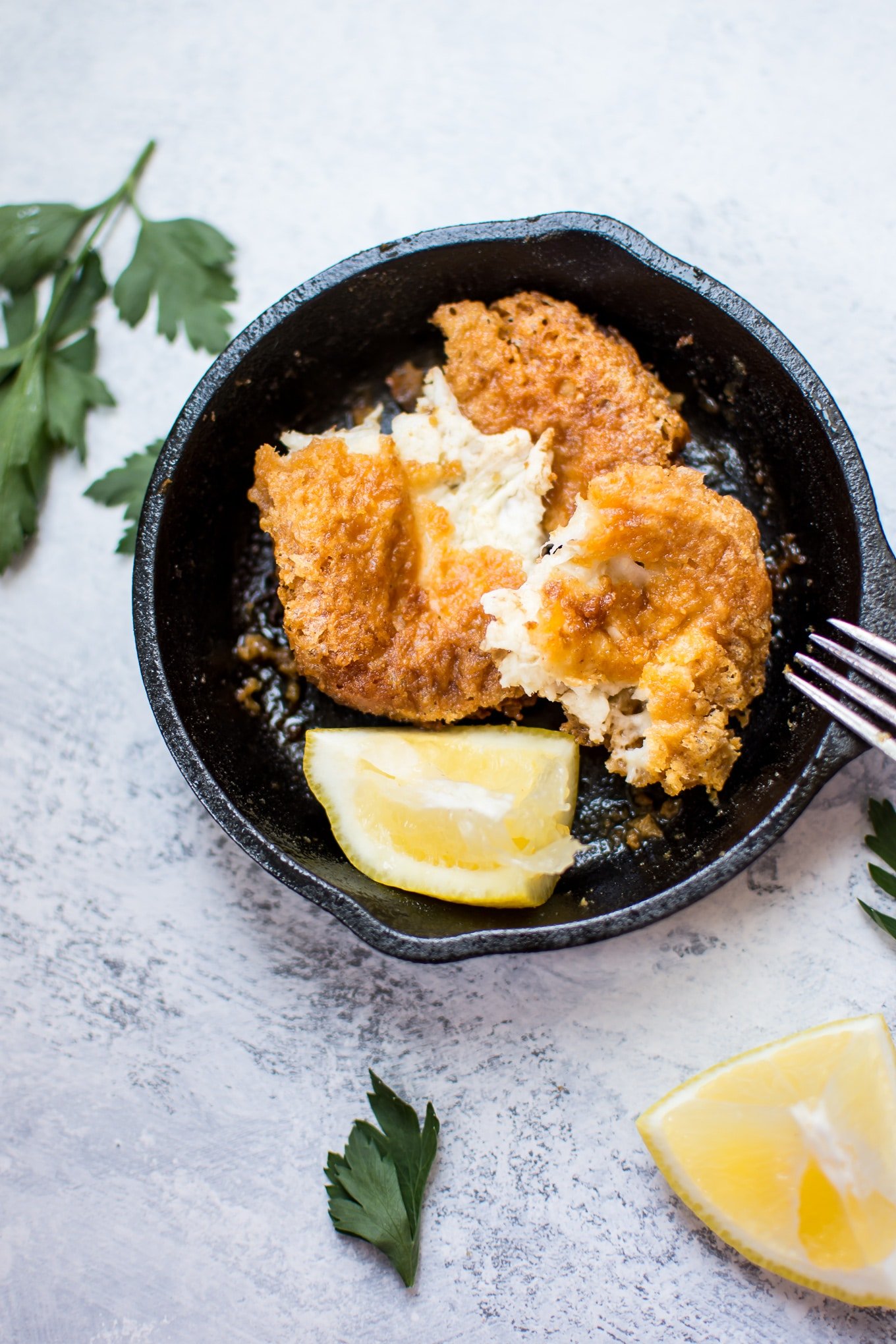 saganaki Greek fried melty cheese in a tiny skillet with a fork and lemon