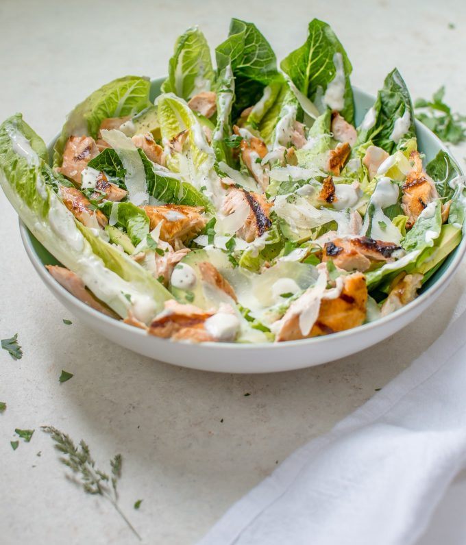bowl of healthy grilled salmon Caesar salad beside a cloth napkin