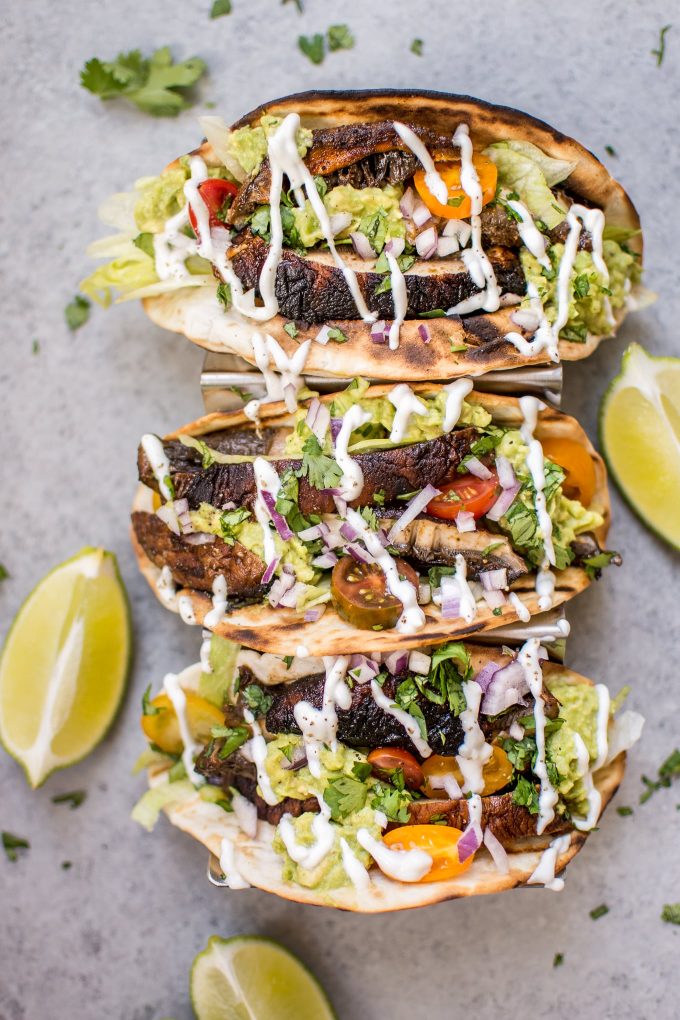 three vegetarian grilled portobello mushroom tacos beside lime wedges