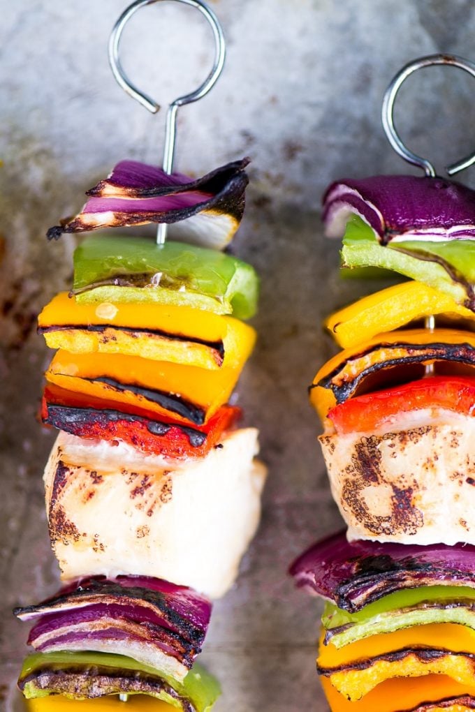 close-up of two chicken skewers with colorful vegetables