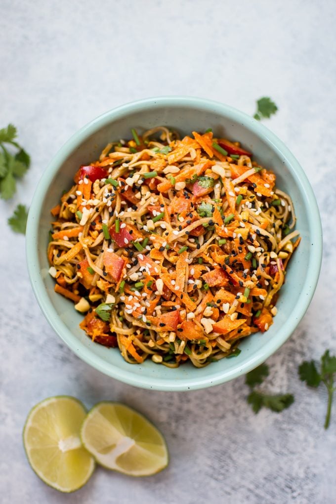 bowl of spicy peanut noodle salad and lime wedges