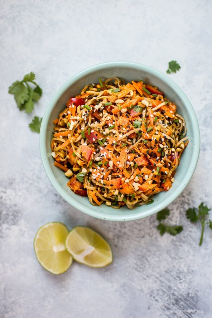 bowl of spicy peanut soba noodle salad with two lime wedges