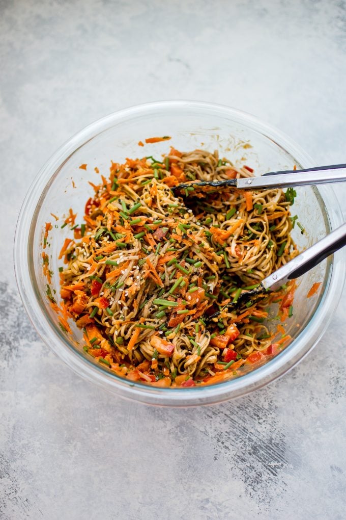 glass bowl with cold soba noodle salad and tongs